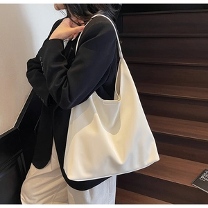 Minimalist large white tote bag shown on shoulder with sleek faux leather texture