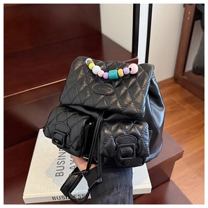 Detail of black quilted mini backpack with colorful beaded handle and dual front pockets