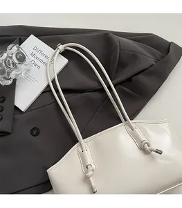 Detail of creamy white tote bag with long knotted straps and fine leather texture