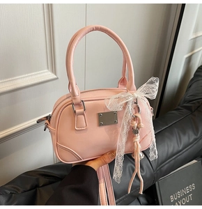 Detail der rosa Lackleder-Handtasche mit silberner Metallplatte und weißem Spitzenschleifen