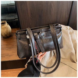 Detail of dark retro leather tote bag with silver buckle and thin shoulder straps