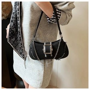 Detail of black denim underarm bag with frayed edges, silver buckle and chain detail