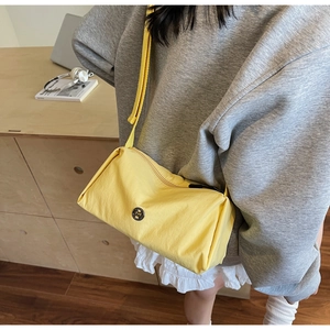 Detail showing the adjustable shoulder strap and yellow nylon fabric of the crossbody bag