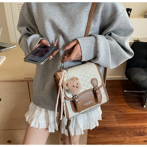 Gros plan d'un sac à bandoulière vintage en cuir marron avec imprimé et peluche d'ours