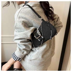 Detail of black denim shoulder bag with silver chain and metal buckle on model