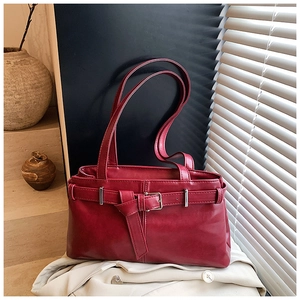 Close-up of deep red vintage shoulder bag featuring a leather bow and buckle detail