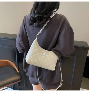 Detail einer gesteppten hellgrauen Hobo-Tasche mit Silberkette und Drehverschluss