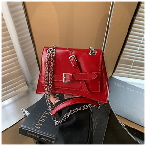 Detail of red faux leather handbag with silver metal buckle and thick chain strap
