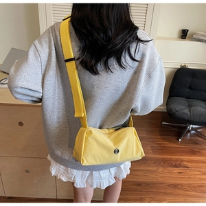 Detail of bright yellow crossbody bag with adjustable wide strap and round logo