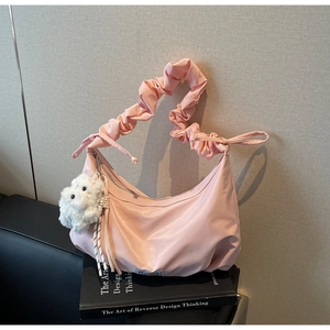 Detail of pink silk nylon crescent bag with ruched strap and plush puppy charm
