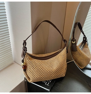 Détail du sac tressé montrant la texture en maille, la bandoulière et le pendentif rétro