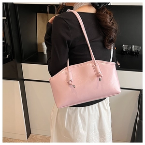 Detail view of pink glossy underarm bag showing patent leather texture and knot shoulder strap