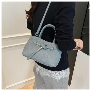 Close-up of Morandi blue textured bucket bag with decorative side knots and slim handle
