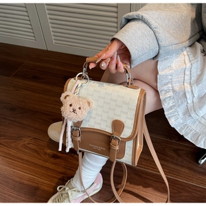 Détail du sac bandoulière étanche avec motif monogramme et pendentif ours en peluche