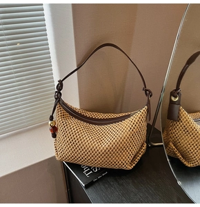 Détail d'un sac en paille tressée avec bandoulière en cuir et pendentif perlé