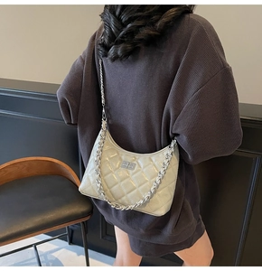 Seitenansicht der hellgrauen Stepptasche mit silberner Kette an einem Model