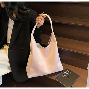 Detail of light pink minimalist hobo tote bag held by a model on a wooden staircase