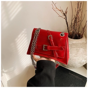 Detail of red patent leather trapezoid crossbody bag with silver chunky chain strap