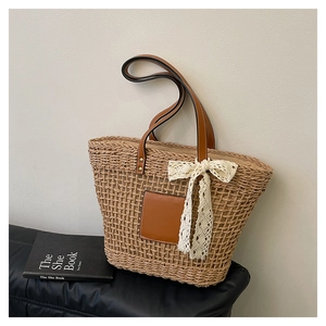 Detailed close-up of woven straw texture with brown leather patch and lace bow detail