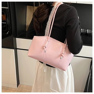 Pink glossy leather tote bag showing detail of slim knotted shoulder straps on a model