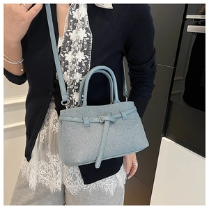 Close-up of light blue crossbody bucket bag with textured pattern and silver buckle detail