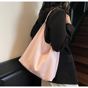 Minimalist soft pink leather tote bag showing wide shoulder strap and side view on model