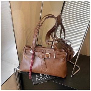 Close-up of brown vintage faux leather underarm bag with buckle and colorful lanyard