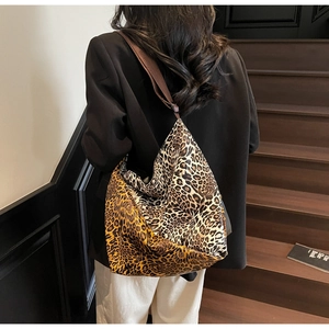 Detail of a large leopard print tote bag with adjustable brown strap worn by a model