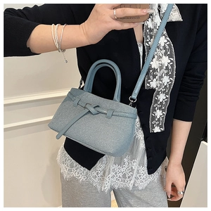 Detailed close-up of light blue twill fabric bucket bag with elegant leather bow detail