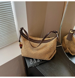 Détail du sac bandoulière en paille avec lanière en cuir et pompon décoratif