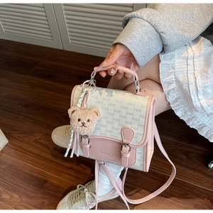 Détail du mini sac à dos rose et beige avec imprimé lettres et porte-clés ours mignon