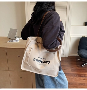 Detail of off-white canvas tote bag featuring brown leather straps and rivet pocket