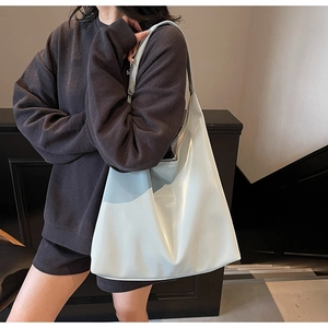 Detailed close-up of a large minimalist hobo tote bag with glossy finish on a shoulder