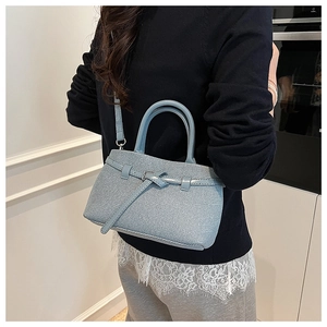 Close-up of light blue woven bucket bag with knot detail and slim shoulder strap