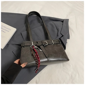 Detail of dark gray leather shoulder bag with vintage buckle and woven key charm