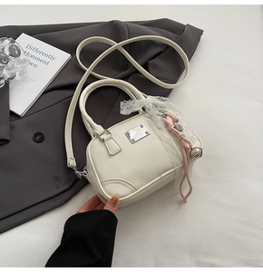 Detail einer weißen Bowlingtasche aus Leder mit Namensschild und Spitzenband-Akzent