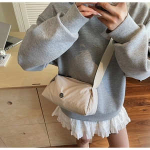 Mirror selfie showing the apricot nylon crossbody bag with wide strap and round logo