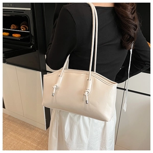 Detail of cream white tote bag featuring knot straps and silver metal hardware tips