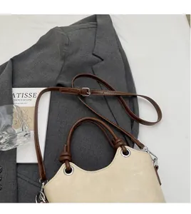 Détail du sac seau crème montrant la bandoulière réglable et la poignée à nœud marron