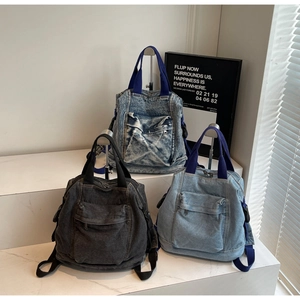 Detailed view of vintage denim backpacks in black and blue on a minimalist white stage