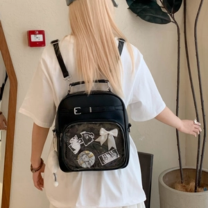 Détail du sac ita noir avec fenêtre transparente montrant des pin's et un nœud blanc