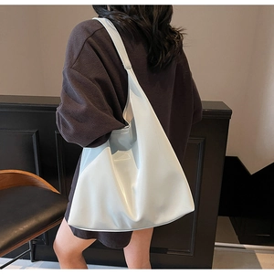 Close-up of glossy cream-colored tote bag with relaxed silhouette and high-shine finish