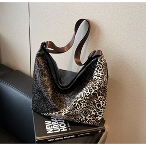 Detail of hobo bag with leopard print and black patchwork design on leather sofa