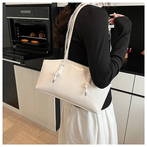 Close-up of white glossy shoulder bag with knot details in a modern kitchen setting