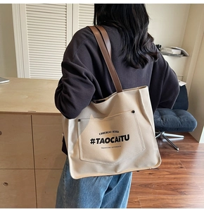 Close-up of minimalist beige canvas tote bag with brown leather straps and printed text
