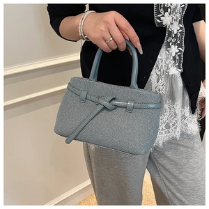 Detailed view of blue fabric texture handbag with stylish leather belt buckle accents