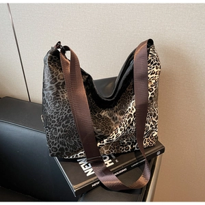 Detailed close-up of large leopard print tote bag with brown adjustable canvas strap