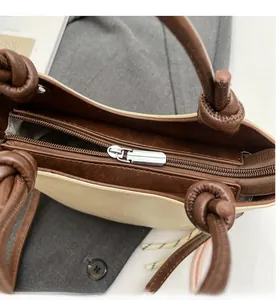 Détail de la fermeture éclair en métal argenté et poignée nouée sur le sac bicolore