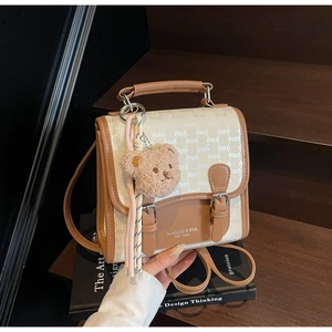 Détail du sac à dos crème avec imprimé de lettres et porte-clés ours en peluche