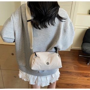 Detail of minimalist beige crossbody bag with adjustable wide strap and metallic M logo